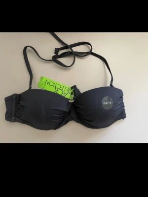 Svart push up-bikini bh - Snygg svart push up-bikini bh från Black Collection med avtagbara och justerbara axelband. Bh:n har vadderade kupor och knäppe fram. Perfekt för dig som vill ha extra lyft och stöd. Materialet känns mjukt och följsamt.