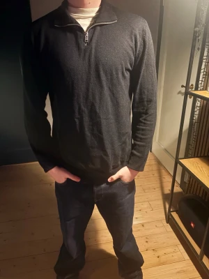Svart halvzip tröja Jack & Jones - Snygg svart långärmad tröja från Jack & Jones med halvzip och hög krage. Perfekt till jeans eller chinos. Tröjan är i mjukt material och har en enkel, stilren design utan tryck eller mönster. 