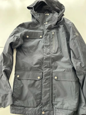 Mckinley jacka  - Snygg parkasjacka med huva och flera praktiska fickor framtill, både med dragkedja och tryckknappar. Jackan har hög krage, justerbar huva och diskret logga på ärmen. Perfekt för kyliga dagar och har en stilren, rak passform. Från mckinley