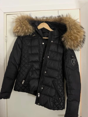 Rock and blue jacka - Snygg svart dunjacka från Rockandblue med stor huva och fluffig fuskpäls. Jackan har väldigt bra skick, då den nästan är oanvänd. storlek 40 men passar också 38. Priset kan diskuteras.