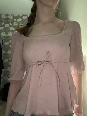 Ljusrosa blus med knyt och volang - Supersöt ljusrosa blus med fyrkantig ringning och knyt i midjan. Perfekt nu när det börjar bli varmare ute☀️🌸