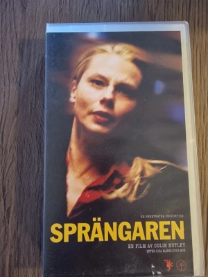 Sprängaren VHS-film - VHS-film med titeln Sprängaren, regisserad av Colin Nutley och baserad på Liza Marklunds bok. Omslaget har gul text och mörka färger med en person i fokus. Filmen är en svensk dramathriller och rekommenderas från 11 år. Speltid cirka 2 timmar och 13 minuter.