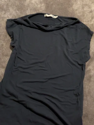 Mörkblå basic t-shirt i bomull - En enkel mörkblå t-shirt med korta ärmar och rund hals. Tillverkad i mjuk bomull som känns skön mot huden. Perfekt att matcha med jeans eller shorts för en clean och avslappnad look.