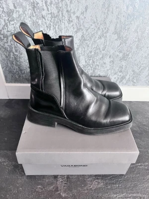 Svarta Chelsea boots från Vagabond - Snygga svarta Chelsea boots från Vagabond i äkta läder med  elastiska sidpaneler. Skorna har dragflikar bak för enkel påtagning och en robust sula. 