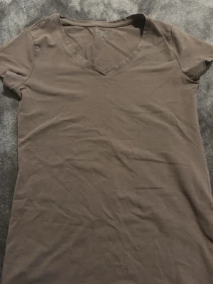 Brun v-ringad t-shirt från Lager 157 - En enkel brun t-shirt från Lager 157  med v-ringning och korta ärmar. Tillverkad i mjuk bomull som känns skön mot huden. Perfekt basplagg att matcha med jeans eller shorts.