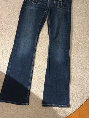 Mörkblå bootcut jeans - Säljer ett par mörkblå bootcut jeans med klassisk femficksdesign och slitna detaljer. Jeansen har breda benslut och kontrastsömmar som ger en snygg vintagekänsla. Perfekta för dig som gillar en avslappnad men trendig stil. Väldigt low waist och är sjukt snygga! Är använda men är inga tecken på användning eller slitningar! Är storlek 158 men skulle säga att dem passar xs! De passade mig när jag var ca 162 cm!! Skriv privat för mått/frågor!
