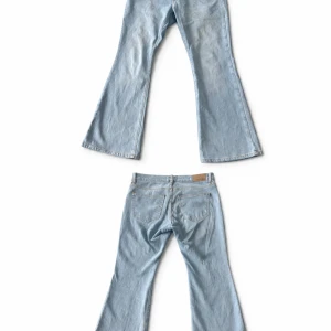 Ljusblå utsvängda jeans - Säljer ett par ljusblå jeans med utsvängda ben och klassisk femficksmodell. Jeansen har en snygg vintagekänsla och är sydda i mjukt denimtyg med kontrastsömmar. Perfekta för dig som gillar retrostil och vill sticka ut lite extra. 