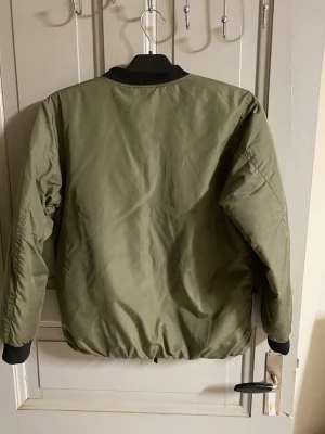 Olivgrön bomberjacka från Cars Jeans - Snygg olivgrön bomberjacka från Cars Jeans med svarta muddar vid ärmslut och krage. Jackan har två bröstfickor med lock, två sidofickor och dragkedja framtill. Klassisk bombermodell i slitstarkt material, perfekt för en cool streetstil.