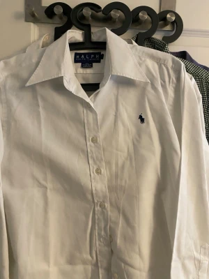 Vit skjorta från Ralph Lauren -  vit skjorta i 100% bomull. Den är använd någon enstaka gång men skicket är bra ändå. Finns inget man ser när man har på den. Jag tror den är i barn storlek för den är ganska så liten den är storlek L KANSKE passar xxs i vanlig storlek men jag vet inte då jag är 190 och trodde det var vanlig storlek när jag köpte den därför säljs den.