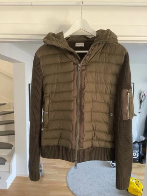 Olivgrön Cardigan med huva från Moncler - Snygg olivgrön Cardigan från Moncler med stickade ärmar och huva. Den har dragkedja framtill, ribbade muddar och en ficka med dragkedja på ärmen. Perfekt för lager-på-lager och streetwear-stil.