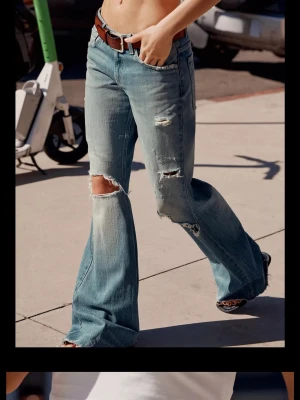 Blå slitna bootcut jeans - Coola blå bootcut jeans med slitningar och hål på benen. Jeansen har en klassisk femficksdesign och är tillverkade i denim. Perfekt för dig som gillar en avslappnad och trendig look.