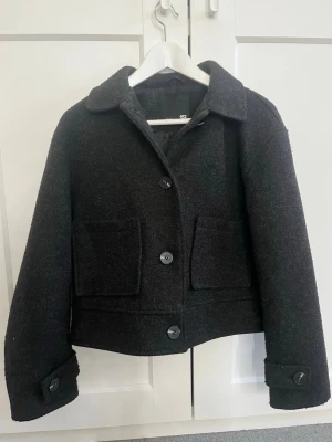 Svart kappa  - Snygg svart kappa från lager 157  med stora knappar framtill och två fickor framtill. Kappan har en boxig, loose passform och klassisk krage. Perfekt till höst och vår.