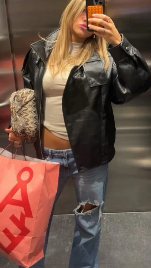 Blå slitna jeans med hål på knät - Säljer ett par ljusblå jeans med lös passform och stort hål på ena knät. Jeansen har låg midja och klassisk femficksdesign. Perfekta för en avslappnad och trendig look.