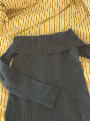 Mörkblå off shoulder stickad tröja - Mysig mörkblå stickad tröja från Gina Tricot med bred off shoulder-krage och långa ärmar. Tröjan har ribbstickade muddar vid ärmslut och nederkant, perfekt för en trendig och avslappnad look.