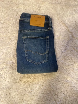 Mörkblå jeans från Jack & Jones - Snygga mörkblå jeans från Jack & Jones med klassisk femficksdesign och kontrastsömmar. Modellen är slim och är tillverkade i slitstarkt denim med lätt tvättade detaljer. Perfekta för en chill och stilren look.