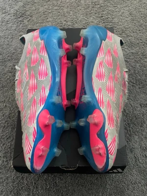 Adidas Predator silver/blå/rosa - Säljer ett par Adidas Predators FG i storlek 42. Orginalbox samt påse finns ej. Inga deffekter eller problem med skorna. Använda ett 20-tal gånger. 