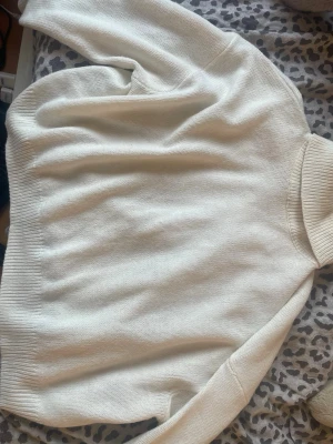 Vit stickad polotröja från H&M - Säljer en vit stickad polotröja från H&M. Tröjan har en hög krage, långa ärmar och ribbade muddar vid ärmslut och nederkant. Perfekt för kyliga dagar och enkel att matcha med olika outfits.