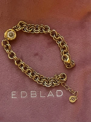 Ocean Gem armband från Edblad NY  - Ocean Gem Bracelet L Gold. Snyggt armband i guldfärgad metall från Edblad med grova länkar och en rund klar sten som detalj. Ocean Gem Bracelet Gold