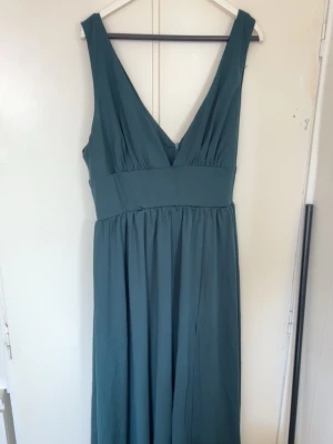 Grön lång V ringad fest klänning  - Knappt använd så den är i väldigt bra skick. Den är insydd i vissa ställen för att det skulle passa bättre men de är väldigt enkla att ta ut ifall man vill det. Har en slit vid vänster ben.  Stl L  men passar också fint för M  Köpt för 500kr