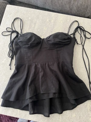 Topp från zara - Fin korsett liknande topp från Zara! Den sitter tajt upptill och går sedan ut nere. Superfin passform och har knytbara band och en dragkedja på sidan! Den ser lite skrynklig ut på bilderna men den har inga defekter😚