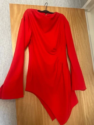 Röd asymmetrisk klänning med markerad midja - Superfin röd klänning med många detaljer ❤️ • Markerad midja och axel som ger en jättefin silhuett • Asymmetrisk mini side dress-design • Öppningar på ärmarna  • Väldigt smickrande passform  Helt ny och oanvänd har tyvärr inte fått chansen att använda den  Nypris 749