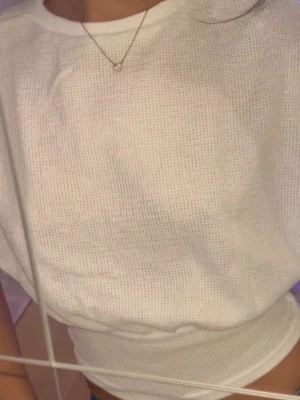 Vit ribbad topp med lös passform - Säljer en vit ribbad topp med lös passform. Toppen har rund halsringning och är tillverkad i ett mjukt, stickat material som känns skönt mot huden. Perfekt att styla med jeans eller kjol för en enkel och clean look.