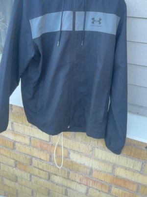 Svart vindjacka från Under Armour - Snygg svart vindjacka från Under Armour bra skick perfekt nu för våren vid frågar hör av dig