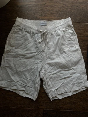 Två par linneshorts  - Säljer två par shorts, ett par vita och ett par svarta. Båda har elastisk midja med snörning och är tillverkade i linne. Perfekta för sommaren och har en avslappnad passform.