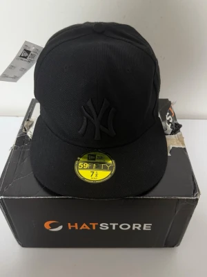 New Era NY 59Fifty Cap – Size 7 1/8 (56,8cm) - Kepsen är helt ny, inga skador eller slitage och tagsen sitter kvar.  Klassisk New Era 59FIFTY fitted-keps med den ikoniska NY-loggan i svart. Stilren design som passar perfekt till alla outfits.  Storlek: 7 1/8 (56,8cm) Rabatt vid köp av flera plagg!