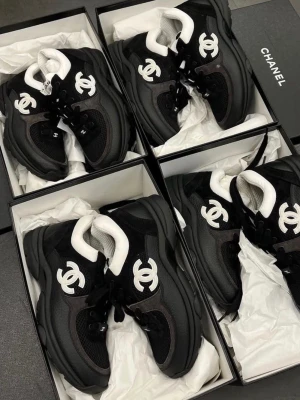 Svarta Chanel sneakers med vit logga - Säljer ett par svarta chunky sneakers från Chanel med den ikoniska vita CC-loggan på sidan. Skorna har en mix av mesh och mockaliknande material, svart sula och vit vadderad insida. Perfekta för dig som vill ha en lyxig och trendig look.