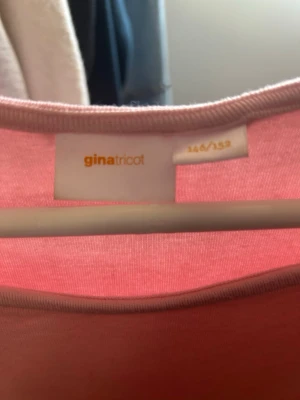 Ljusrosa topp från Gina Tricot - Söt ljusrosa topp från Gina Tricot med korta ärmar och rund halsringning. Enkel och stilren design som passar perfekt till jeans eller kjol. Tillverkad i mjukt material för en bekväm känsla hela dagen.