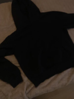 Svart hoodie med huva - En enkel och stilren svart hoodie med huva och långa ärmar. Hoodien har ribbade muddar vid ärmslut och nederkant. Perfekt för dig som gillar en clean och avslappnad look.