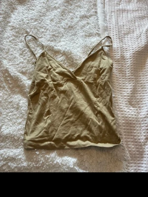 Beige linnetopp från Weekday - Säljer en beige linnetopp från Weekday med tunna axelband och v-ringad hals. Toppen är i mjuk bomull och har en enkel, stilren design som passar perfekt till sommaren. Superskön och lätt att matcha med allt!