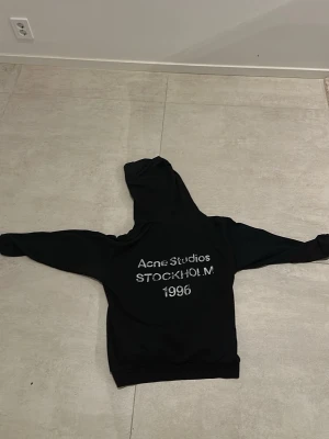 Svart hoodie Acne Studios Stockholm - Svart hoodie från Acne Studios med tryck på ryggen där det står 'Acne Studios STOCKHOLM 1996'. Köpt på Vestiaire Collective för ungefär 1 år sedan.  Klassisk passform med huva och långa ärmar. Perfekt för dig som gillar stilrena och trendiga plagg. Materialet känns mjukt och bekvämt. ❗️PRISET GÅR ATT DISKUTERAS❗️