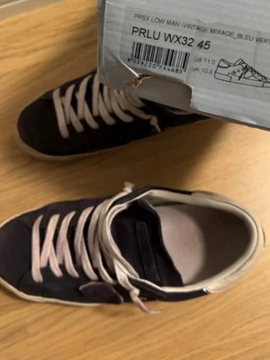 Phillipe Model sko - Snygga phillipe model sko med vita snören och vita detaljer runt kanten. Skorna har en klassisk låg siluett och är tillverkade i mockaliknande material. Perfekta för dig som vill ha en stilren och enkel look till vardags.