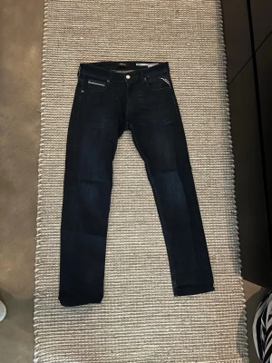 Mörkblå jeans från Replay - Snygga mörkblå skinny jeans från Replay med klassisk femficksdesign och silverfärgad knapp. Jeansen har en smal passform och är tillverkade i stretchigt denimtyg för extra komfort. Perfekta till en avslappnad streetstyle-look. Har klippt ner dom lite, så skulle säga att dom sitter mer som L32. 