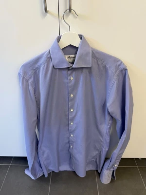 Blå skjorta från Stenströms, stl 37 - Snygg blå skjorta från Stenströms i fitted body-modell. Tillverkad i 100% bomull med diskreta vita knappar och klassisk krage. Perfekt för dig som gillar stilrena och tidlösa plagg.