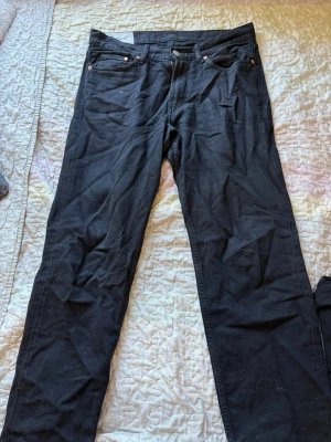 Svarta raka jeans - Säljer ett par svarta jeans med rak passform och klassisk femficksdesign. Jeansen har bälteshällor, knappgylf och är tillverkade i ett mjukt denimtyg. Perfekta för dig som gillar en enkel och stilren look.