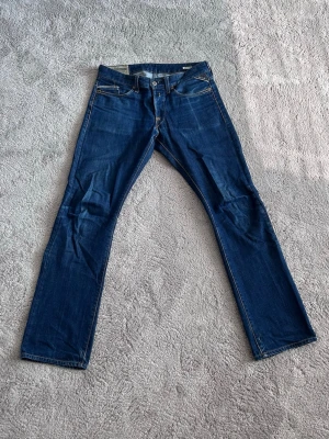 Mörkblå raka jeans från Replay - Snygga mörkblå jeans med raka ben och klassisk femficksdesign. Jeansen har kontrastsömmar och normal midja. Perfekta för en avslappnad och stilren look. Materialet är denim i bomull.
