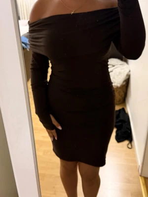 Brun offshoulder klänning - Säljer denna korta bruna långärmade offshoulder klänningen från h&m. Klänningen har även ett tumhål och är väldigt figurnära. Den är i storlek s men jag som vanligtvis har storlek xs tycker den passar mig bra, är i väldigt bra skick endast använd ett par timmar💕