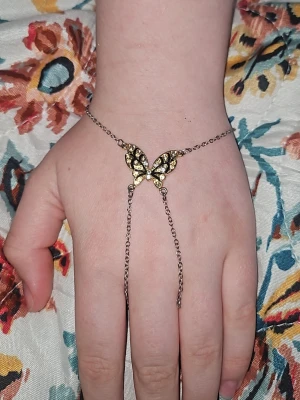 Silverfärgat armband med fjäril - Unikt armband i silverfärg med en dekorativ fjäril i mitten, prydd med små glittrande pärlor. Kedjan är tunn och smidig, och fjärilen har en elegant design som verkligen sticker ut. Perfekt accessoar för dig som gillar detaljer och vill ha något extra till din stil.