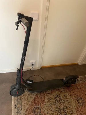 Elscooter Xiaomi svart - Säljer en svart elscooter från Xiaomi med robust ram i metall och bred ståplatta. Scootern har gråa handtag, röda detaljer på bromskabeln och stora hjul för smidig körning. Perfekt för att ta sig runt i stan och laddas enkelt via eluttag.Scootern är använd varsamt och är i mycket bra skick, fungerar utmärkt. Maxhastigheten ligger på 20 km/h och batteritiden håller upp till 60 km. Laddare medföljer. Priset kan diskuteras!