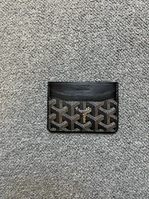 Svart kortfodral från Goyard - Snyggt svart kortfodral från Goyard med klassiskt mönster i vitt och brunt. Fodralet har flera kortfack och är gjort i läder med canvasdetaljer. Perfekt för dig som vill ha en stilren och exklusiv accessoar i fickan.