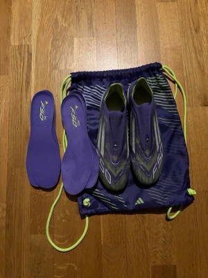 Adidas F50 lila fotbollsskor - Säljer ett par Adidas F50 fotbollsskor. Väldigt fina adidas fotbollsskor F50 modell.  liten skada på vänster sko men absolut inget man märker. Det hände första träningen med skorna så skorna är bara använda 1 vecka.  Storlek 41 1/3