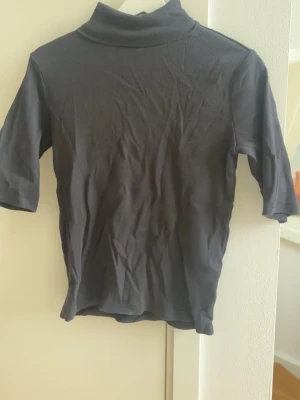 Mörkgrå ribbad polotopp - Snygg mörkgrå polotopp med ribbad struktur och halvlånga ärmar. Perfekt att styla med jeans eller kostymbyxor. Från lager 157!