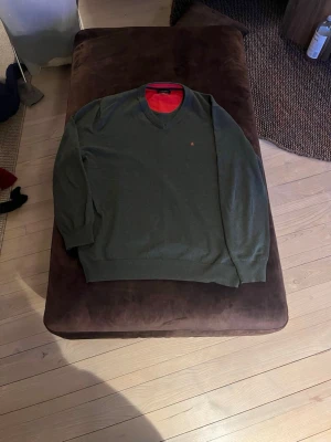 Mörkgrön tröja från Park Lane - Snygg mörkgrön tröja från Park Lane med rund halsringning och diskret logga på bröstet. Insidan av kragen har en kontrasterande röd färg som ger en cool detalj. Perfekt till jeans eller chinos för en clean look.