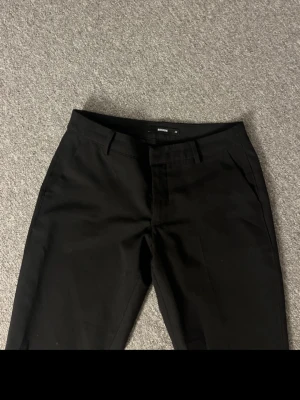 Svarta kostymbyxor från Bik Bok - Snygga svarta kostymbyxor från Bik Bok med raka ben och klassisk passform. Byxorna har hällor för skärp och diskreta fickor framtill. Dom är lågmidjade 