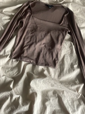Brun mesh topp med lång ärm - Snygg brun mesh topp med lång ärm och rund halsringning. Tunn och lätt transparent, perfekt för lager på lager. Croppad passform som ger en trendig look. Enkel att styla till olika outfits.