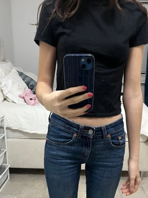 Svart croppad t-shirt - En enkel svart croppad t-shirt med rund hals och korta ärmar. Perfekt basplagg som är lätt att matcha till olika outfits. Tillverkad i mjuk bomull för en bekväm känsla.