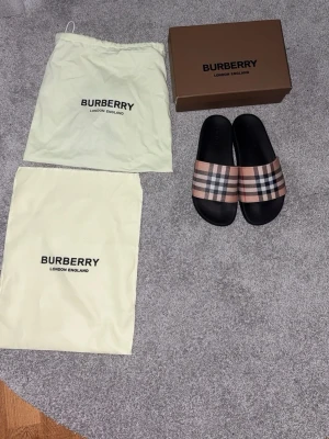 Burberry sandaler med rutigt band - Ett par burberry tofflor som aldrig är använda, allt på bilden med kommer, Storlek 40-41